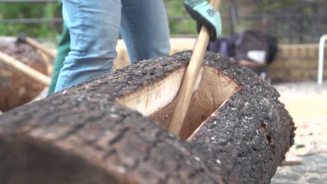 Close-up-woodworker-with-axe-working-on-the-inside-of-a-log-trunk-he-is-hollowing