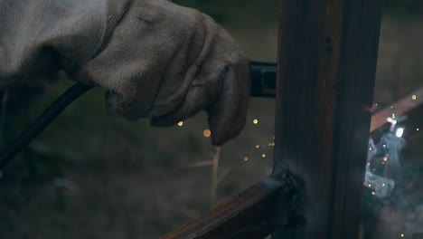 trabajador de cámara lenta en soldaduras de guantes partes de la valla de la casa