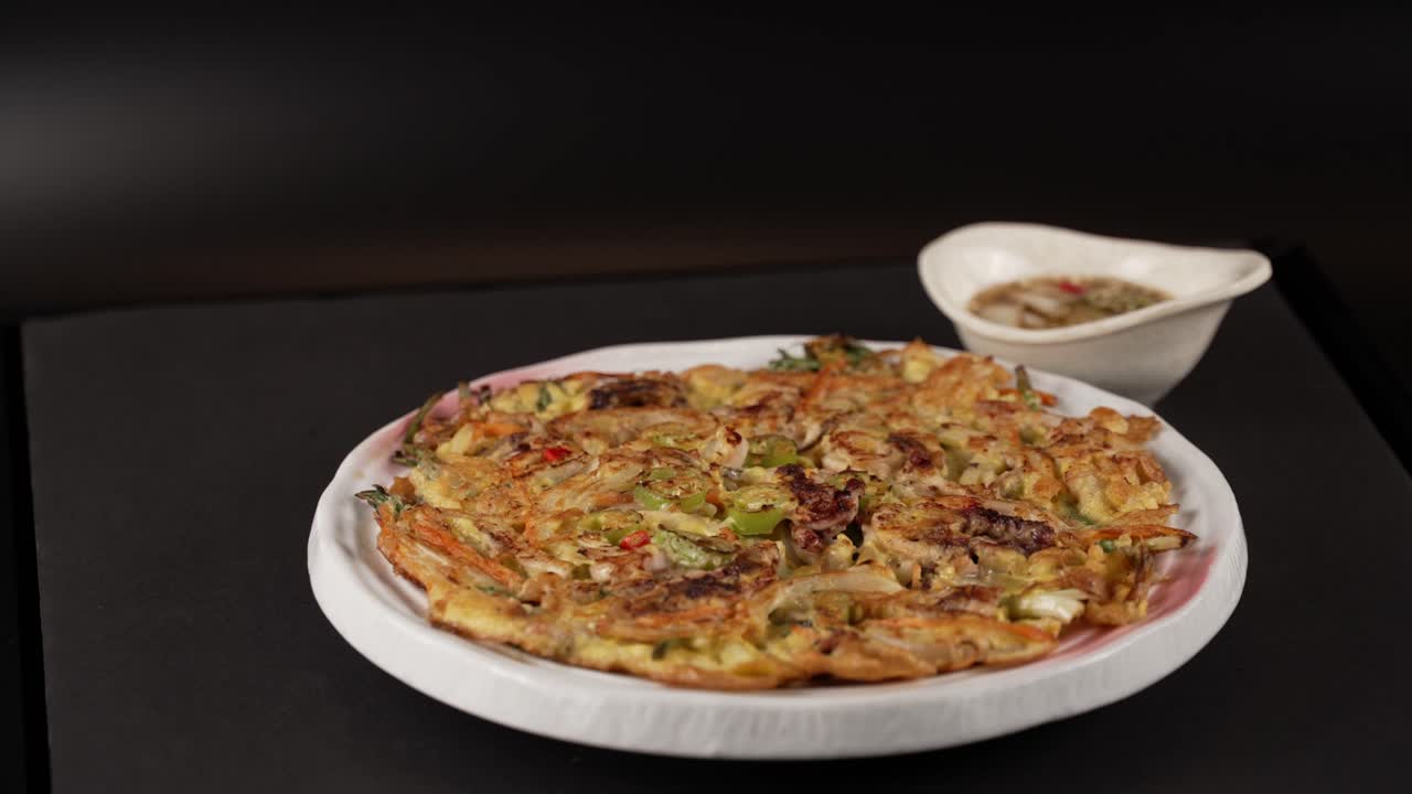 A crispy seafood scallion pancake with rich flavors, best paired with spicy soy sauce. 풍부한 맛을 지닌 바삭한 해물 파전이 매콤한 간장 소스와 가장 잘 어울립니다.