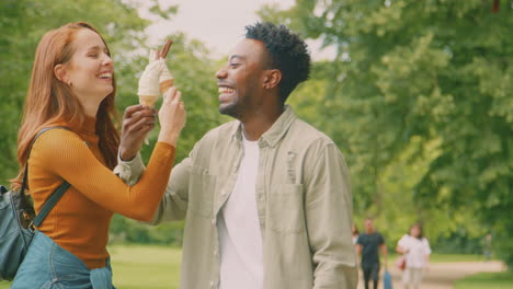 Young-Couple-Travelling-Through-City-Together-Eating-Ice-Creams-In-Park