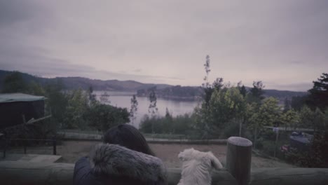 hd of a woman and her dog outdoog house in front of a lake