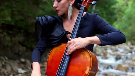 Luxury woman plays the cello. Beautiful girl violinist playing violin on summer landscape. Attractive woman in black dress enjoying musical art while playing instrument.