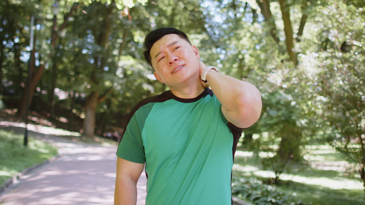 Asian man have shoulder neck joints pain sport injury concept after running in park outdoors