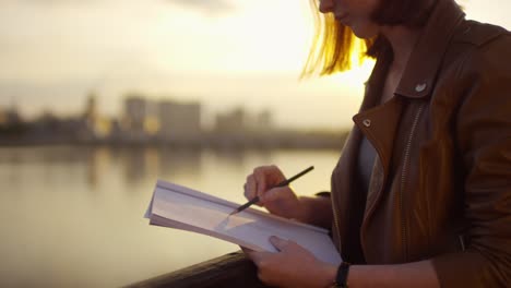 primer plano de una linda chica de jengibre dibujando al aire libre al atardecer