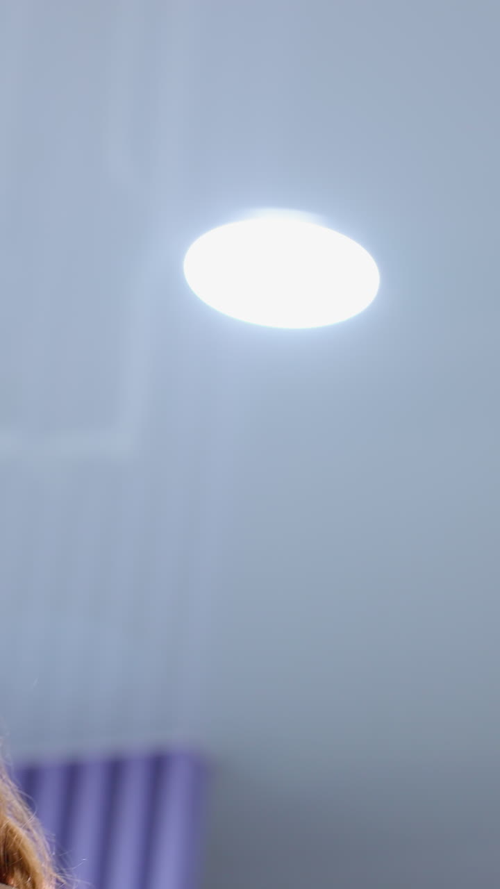 mujer en traje de entrenamiento marrón realiza un ejercicio de fitness, levantando un rodillo de espuma arriba y abajo, luces brillantes del gimnasio iluminan su expresión enfocada mientras se involucra en entrenamiento de fuerza y resistencia