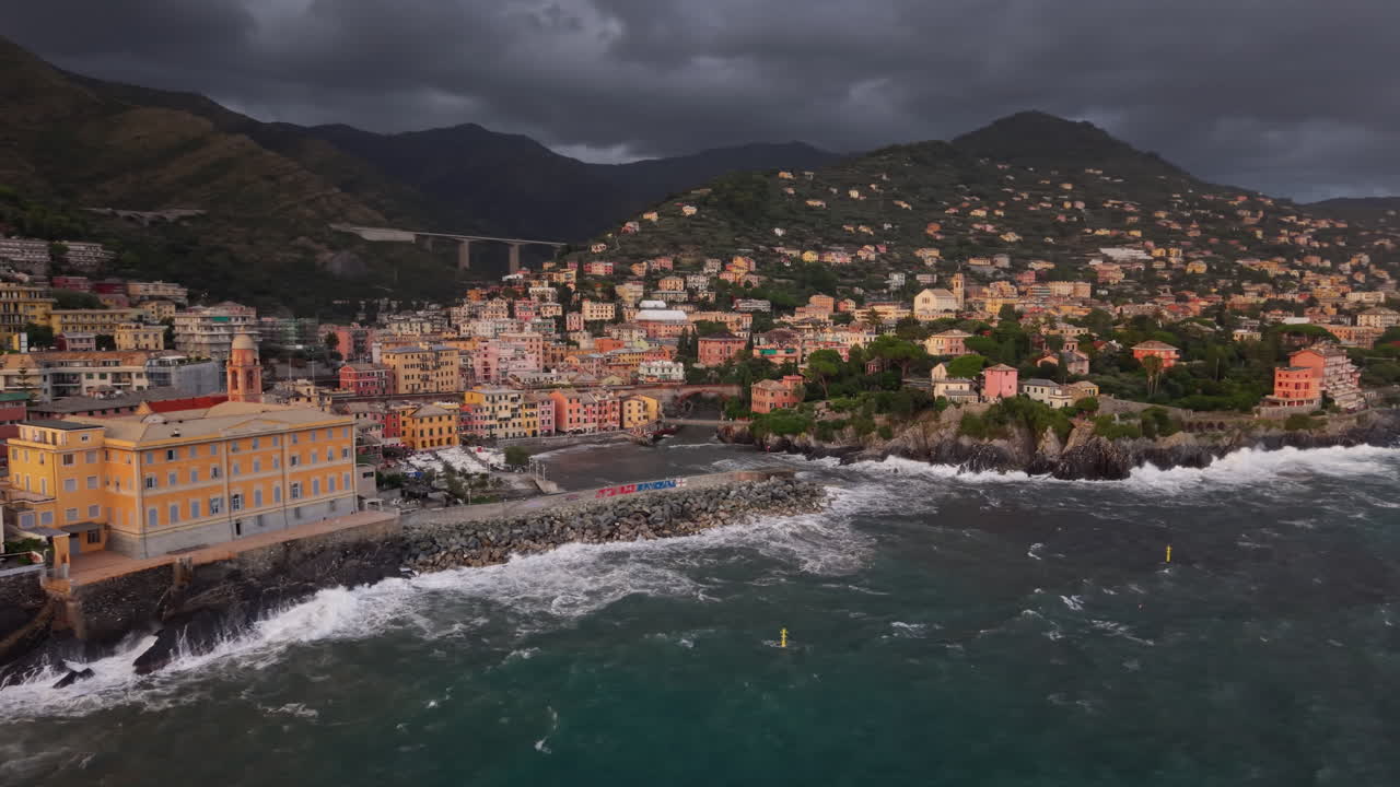 Slow-motion view of coastal town under stormy clouds and rolling waves