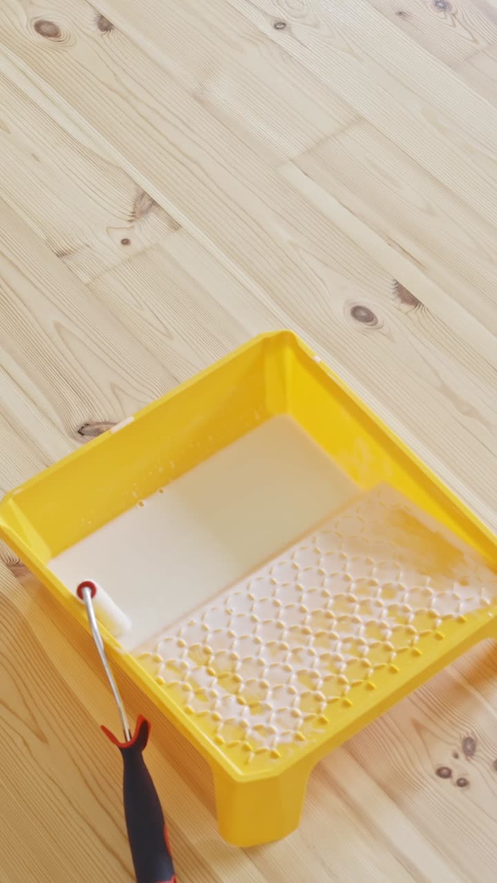 Laying varnish on hardwood floor with tools, renovation focus