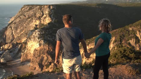 married couple of tourists standing at cliff