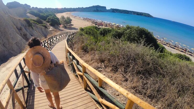 Young woman walking towards Zante beach on wooden walkway, Zakynthos island, Greece.