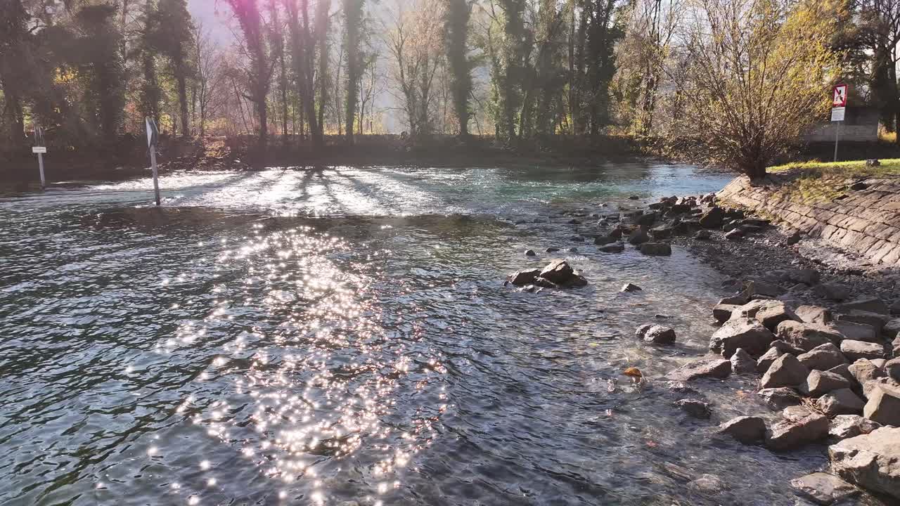 Sunlight dances on the rippling waters of the river flowing into Lake Walensee, creating a scene of tranquil beauty and boundless freedom amid the Swiss landscape.