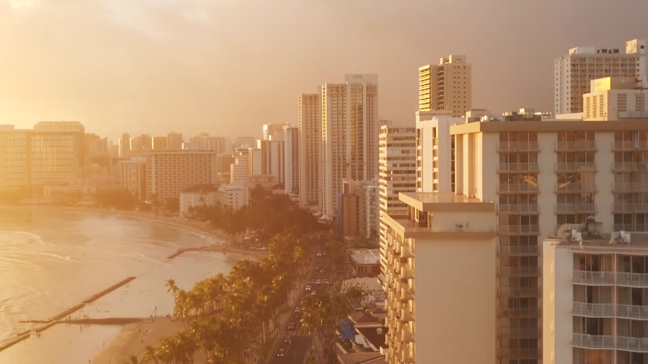 Drone aéreo panorâmico voando lentamente sobre o colorido horizonte de Honolulu durante o pôr do sol em Oahu, Havaí, com a Praia de Waikiki como um ponto de interesse especial