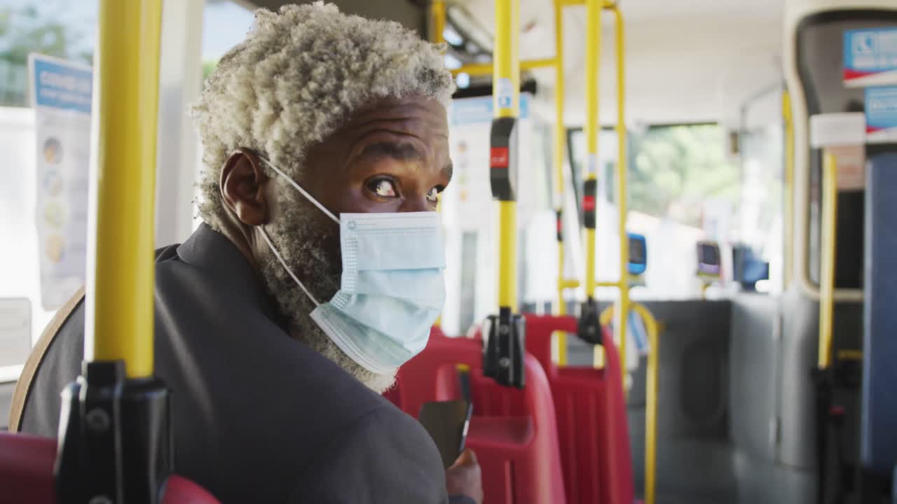African american senior man wearing face mask travelling in the bus
