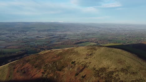 early sunlight on highland mountain peak aerial view across vast frosty idyllic farmland countryside wilderness pull back shot