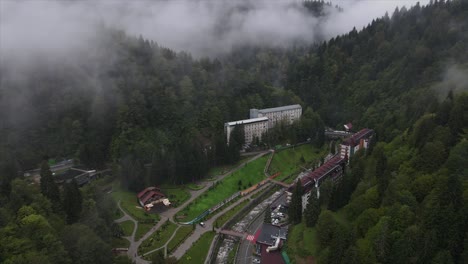 top view shot of fog passing through green mountains valley country road hotel spa restaurant river bridge