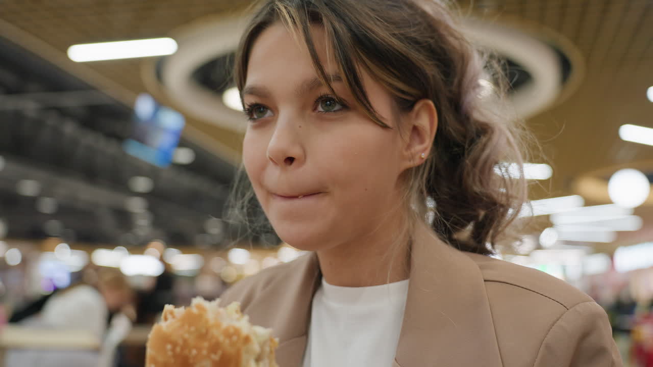 Vivace ragazza gusta un pasto delizioso, giovane donna energica assapora con piacere un croccante hamburger, vivace adolescente assapora con passione un gustoso e croccante hamburger con entusiasmo