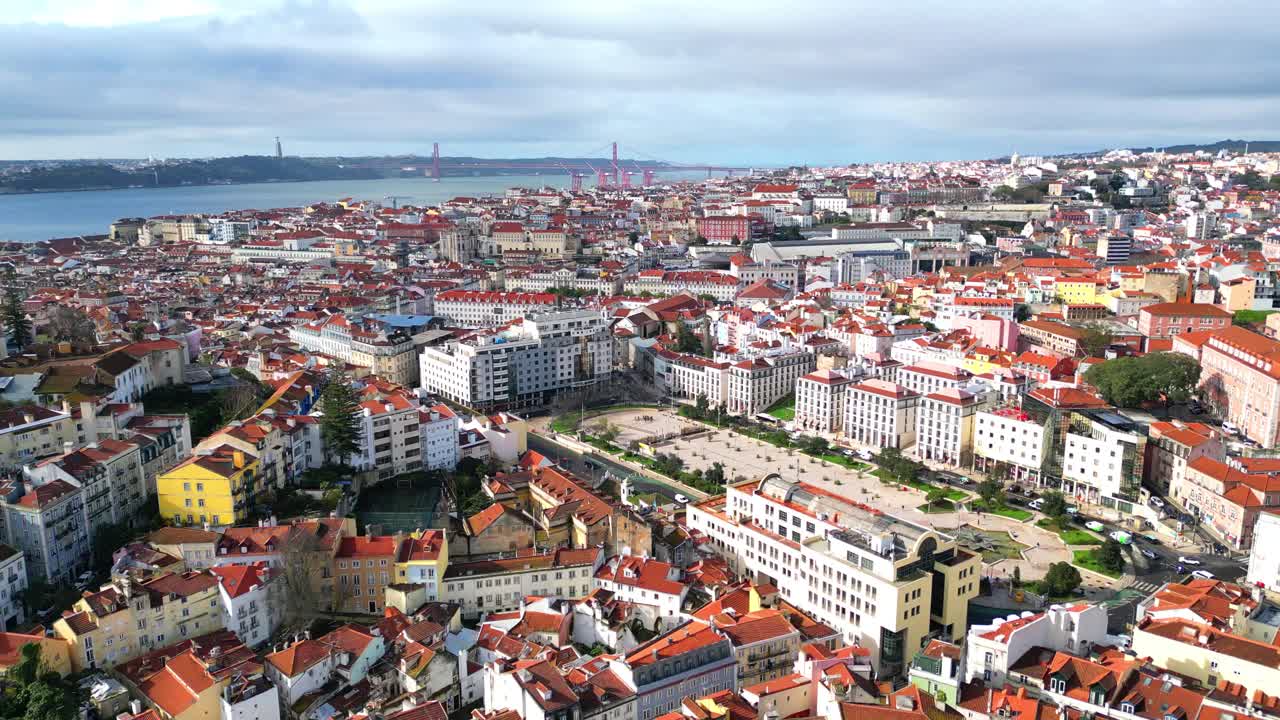 Volando all'indietro sopra la città di Lisbona, con vista da Piazza Martim Moniz, con lo skyline di Lisbona e il fiume Tago sullo sfondo, Portogallo