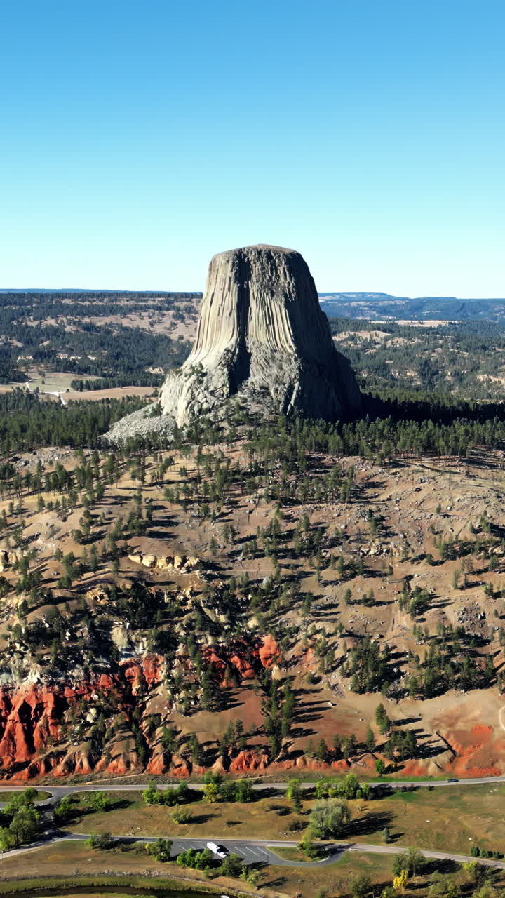 Luftfoto med drone av Devils Tower National Monument som stiger dramatisk opp over det omkringliggende landskapet i Wyoming, USA. Vertikalt.