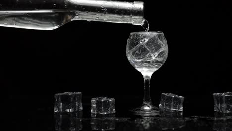 pouring vodka into a glass with ice cubes