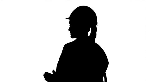 silueta de una ingeniera con casco de seguridad sentada y hablando