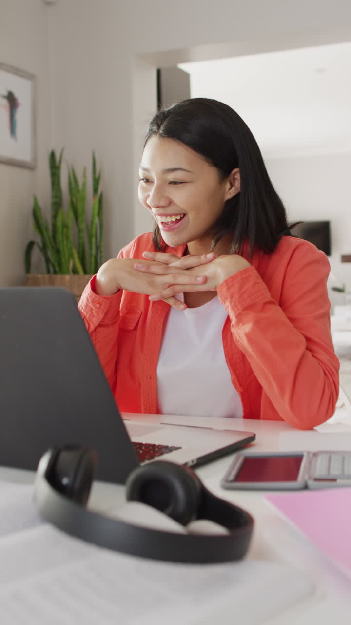 Vertical video of smiling biracial woman with dark hair on laptop video call