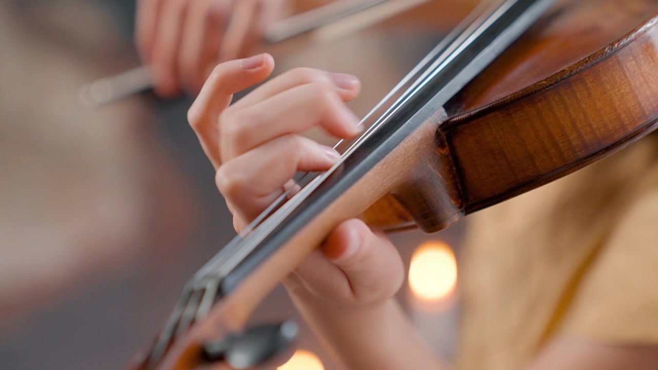 Close-up of Musician's Hands Playing Violin Strings
