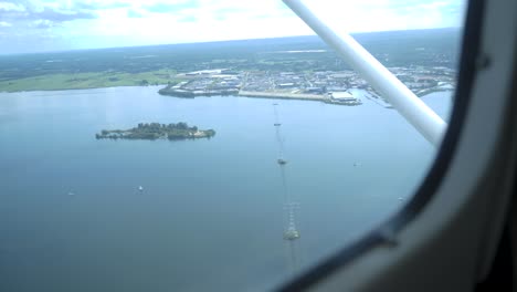 An-aerial-view-of-a-lake-in-Europe,-The-Netherlands-with-green-nature,-an-island,-cell-tower-masts-and-a-town-in-the-frame