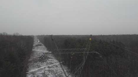 Drone-going-through-power-lines-and-cables-in-brodnowski-snowy-forest-in-warsaw-poland