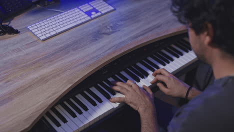 caucasian-musician-playing-piano-in-his-home-studio