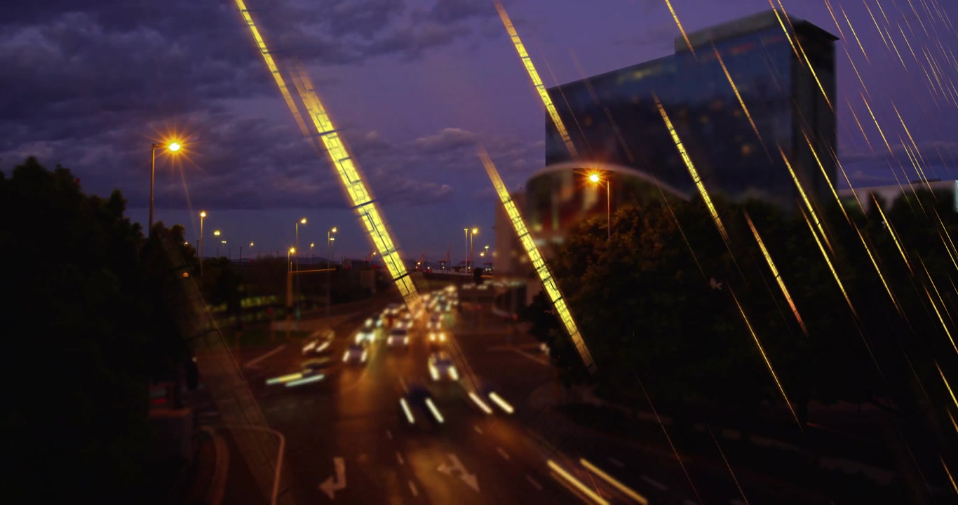 Slow shutter causing cars streaming into intersection forming golden light streaks as sky darkening