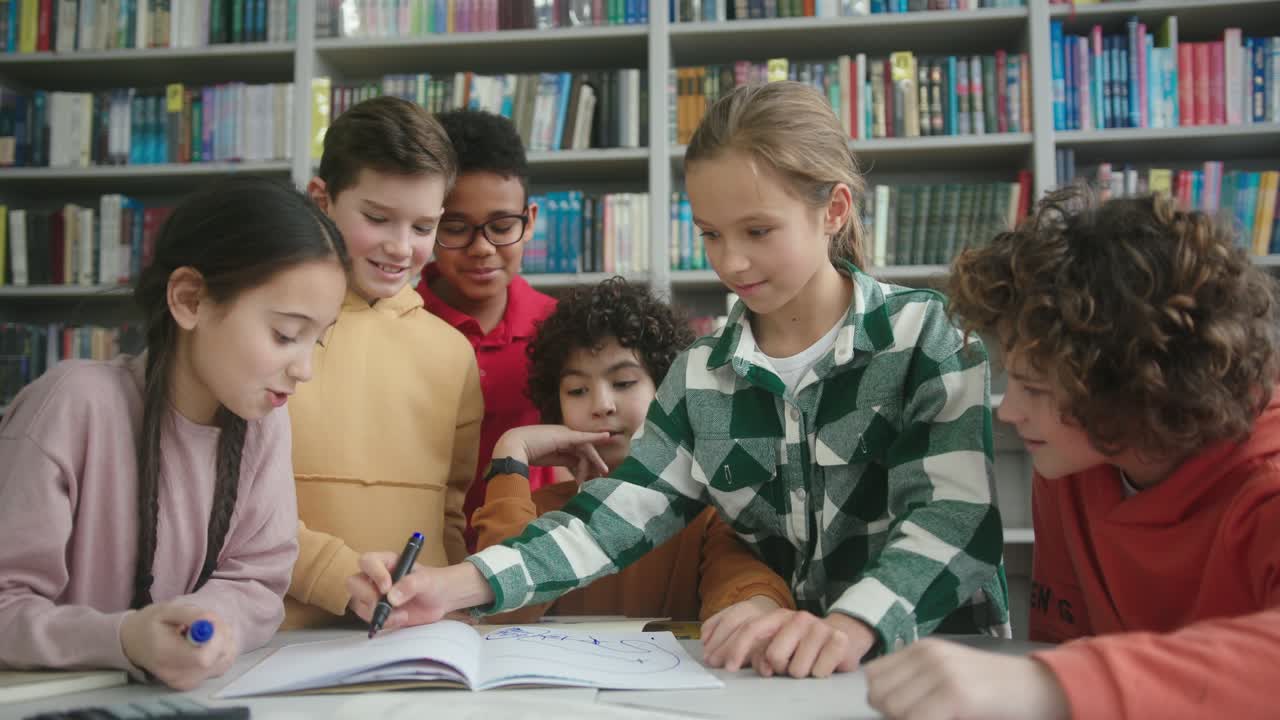 금발 소녀는 도서관에서 운동책에서 마커로 그림을 그립니다.