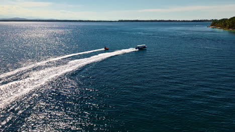 inflatable sofa towed by speedboat in the ocean to the beach in summer in bocas del toro province, panama. - aerial shot
