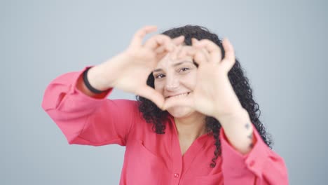 mujer joven haciendo una señal de corazón a la cámara.