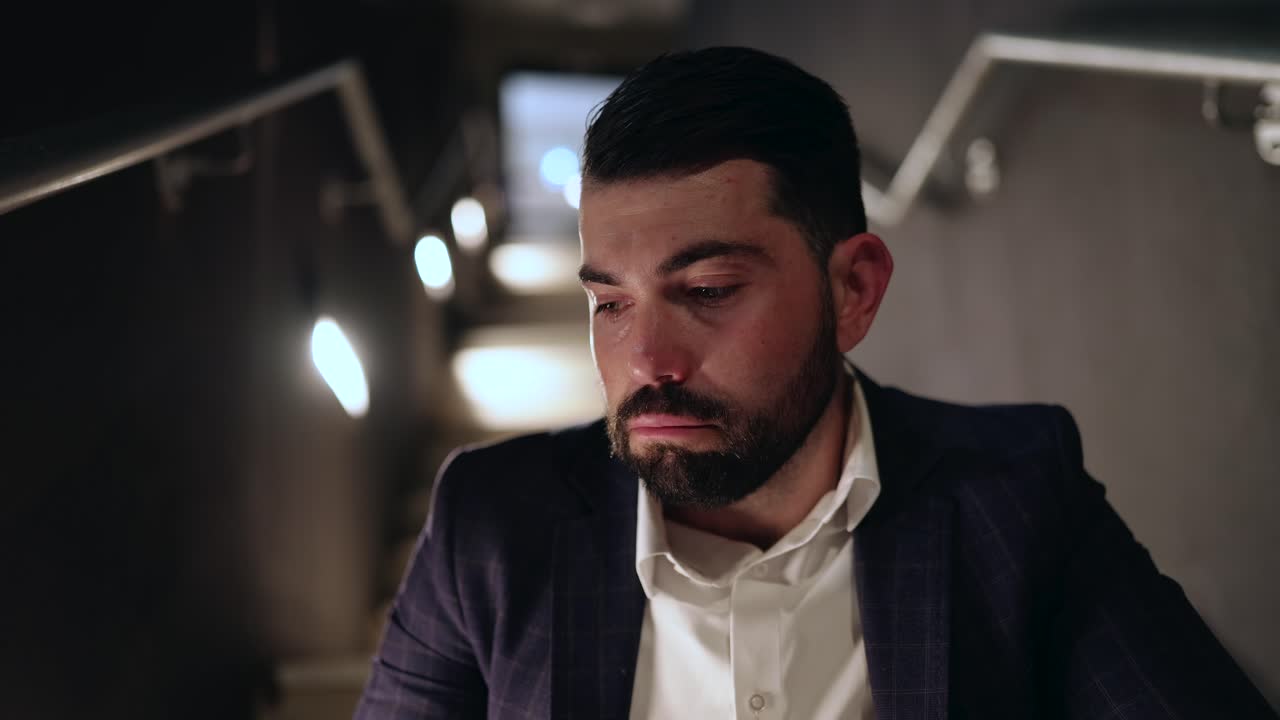 Uomo d'affari seduto sulle scale fuori dall'ufficio di notte, pensieroso e in contemplazione.