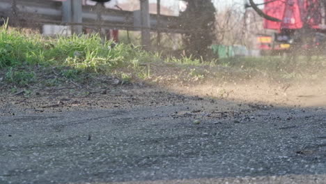 Slow-Motion-Shot-Of-A-Blower-Blowing-Sand-and-Dirt-Off-the-Concrete-Road---Close-Up-Static-Shot