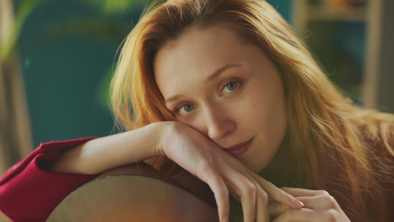 카메라 앞에서 기타를 들고 포즈를 취하는 여자