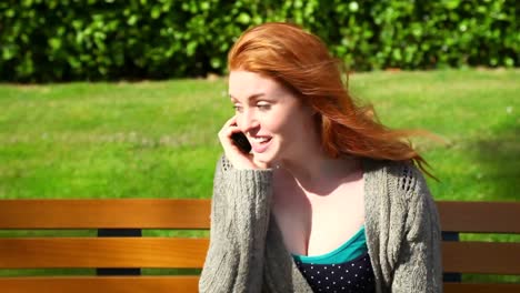 cute woman sitting on bench while phoning