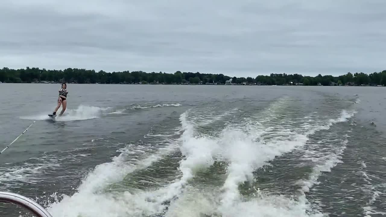 Person wakeboarding behind boat at a lake