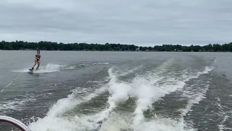 person wakeboarding behind boat at a lake