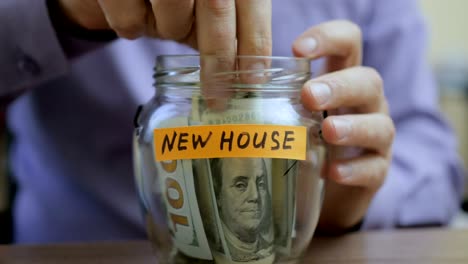 caucasian man putting a glass jar put in a drawer table with his savings for future new house