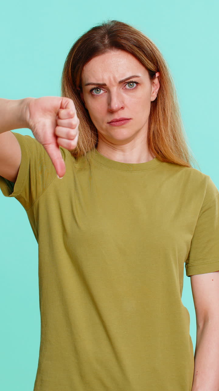 Adult woman showing thumbs down with serious face expressing dislike disapproval negative feedback