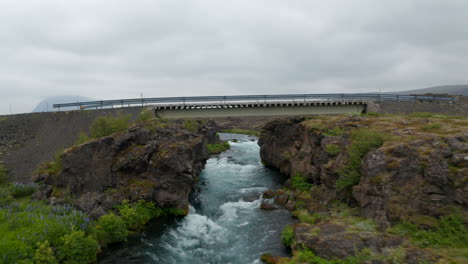 Drone-view-amazing-wild-countryside-in-Iceland,-with-river-flowing-in-rocky-formation-riverbed.-Aerial-view-landscape-of-isolated-and-adventurous-icelandic-highlands-with-powerful-river-flowing