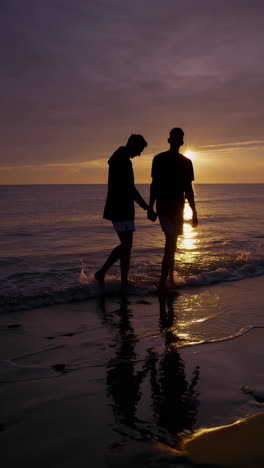 couple walking hand-in-hand on a beach at sunset