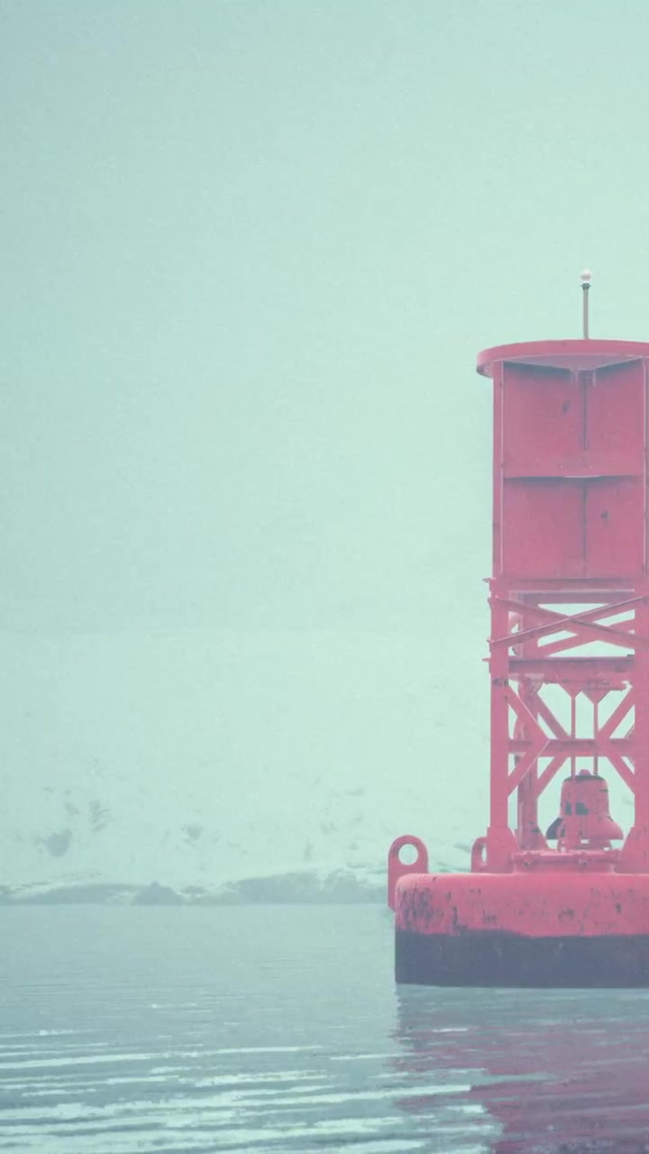 Buoy floating in water with clouds and mist in the distance during a calm day