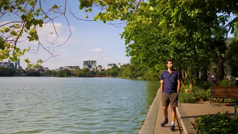 Ein-Junger-Mann-Am-Seeufer-Denkt-über-Die-Schönheit-Des-Hoan-Kiem-Sees-Und-Der-Stadt-Dahinter-Nach