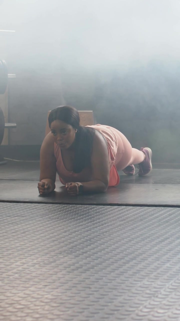 Video verticale: Donna in completo rosa che esegue un plank sugli avambracci su un tappetino da palestra per rafforzare il core.
