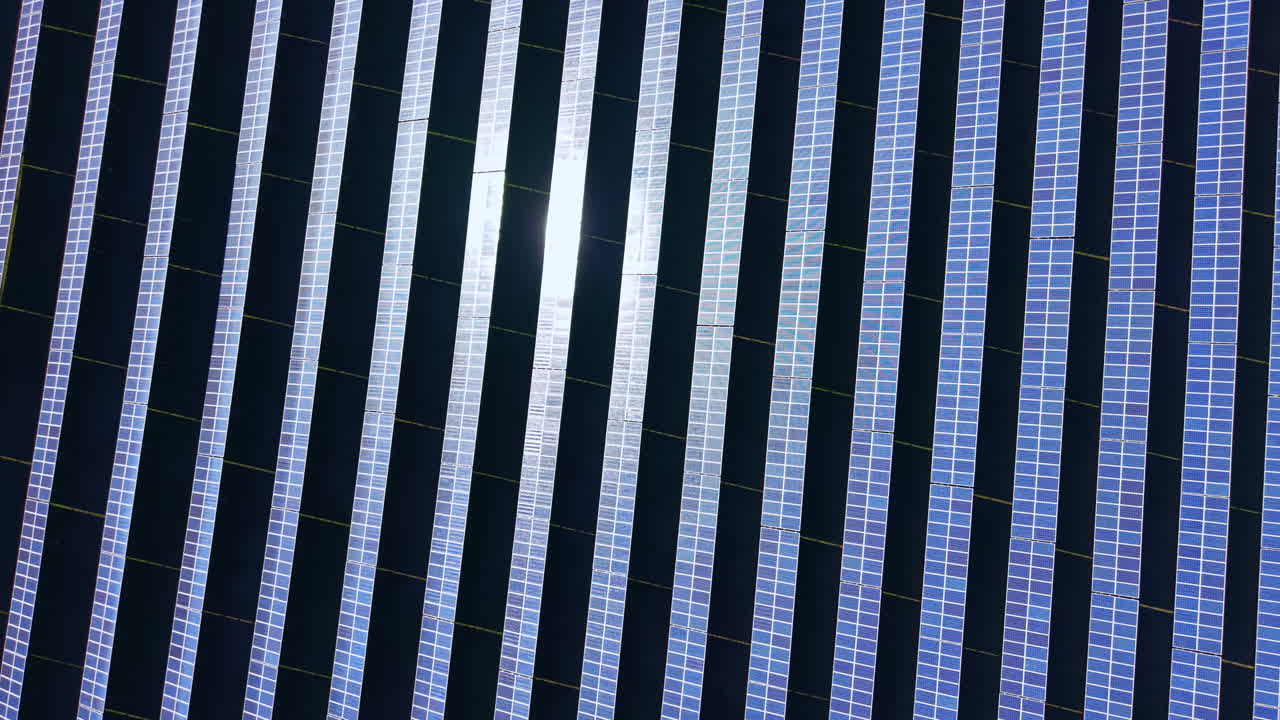 I pannelli solari sono disposti in file ordinate in un parco solare con la luce del sole che si riflette sulla superficie durante il giorno.