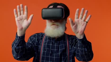 Senior-stylish-gray-haired-man-using-headset-helmet-app-to-play-simulation-virtual-reality-VR-game