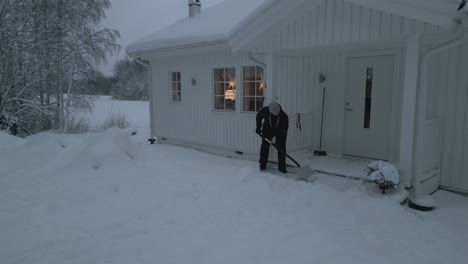 mujer limpiando la nieve frente a su casa