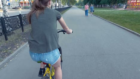 side view of a girl cycling on a road with flowers in a basket and exploring the city, slow mo, steadicam shot