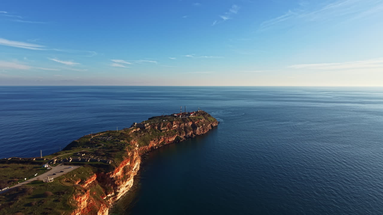 Vista della costa rocciosa con scogliere e oceano durante le ore diurne con cielo sereno che si affaccia sull'orizzonte
